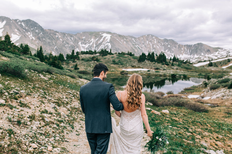 Photo of couple walking with mountains and lake in the background