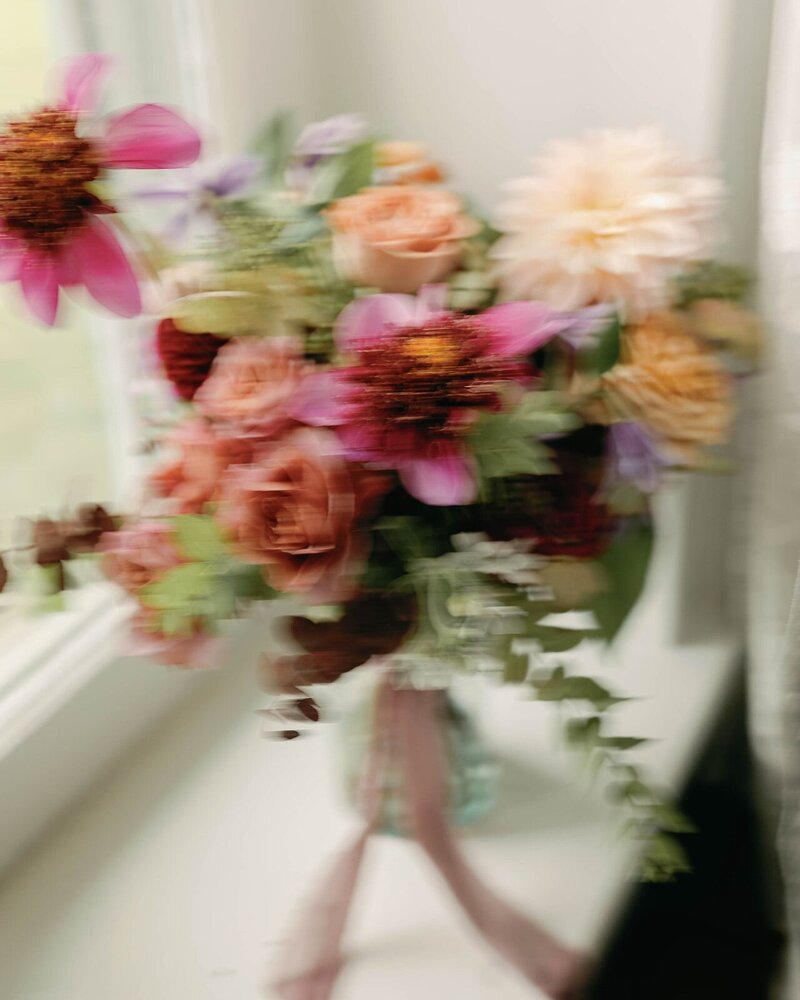 Blurry vibey bridal bouquet photo with purple dahlias and greens