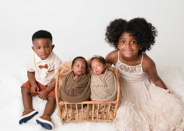 big sister and toddler brother beside swaddled newborn twins in basket — Birmingham AL studio