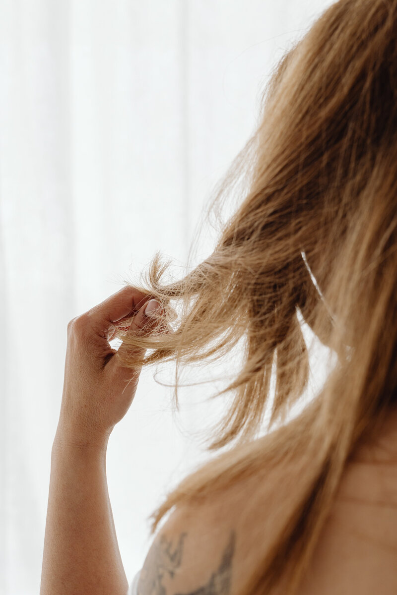 Woman in front of a window playing with her hair