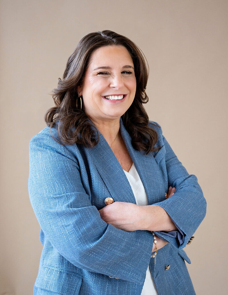 Dr. Chris Limone in a magenta blouse sitting at a desk with a branded mug and laptop, looking approachable and professional