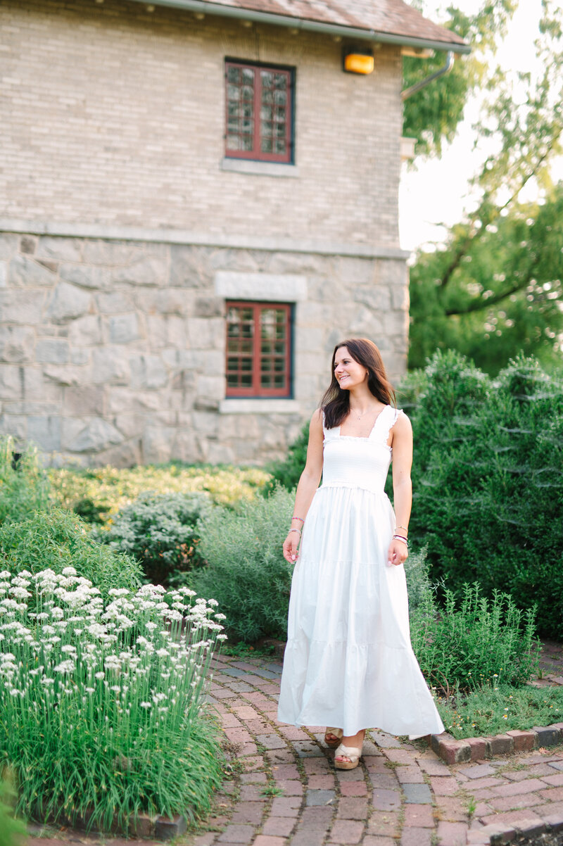 a girl walking on a landscaped pathway beside a stone house