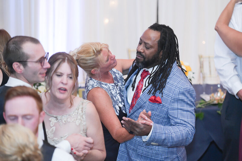 DJ Marz laughing with a group of guests during a lighthearted wedding moment at the reception.