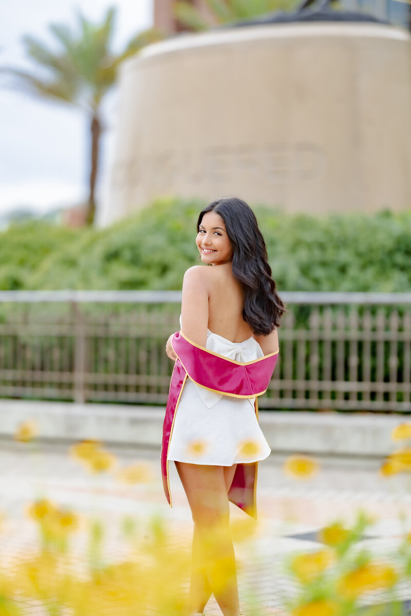 Graduate standing with her cap and gown during her senior photoshoot in Tallahassee, Florida.