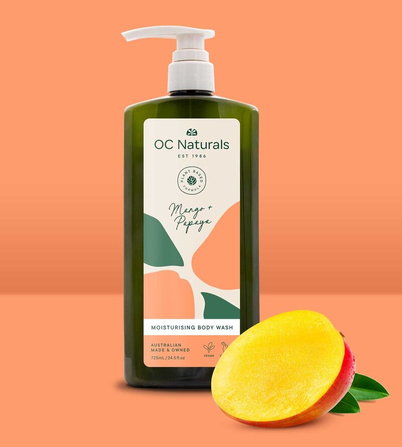 Dark green body wash bottle with beige pump featuring label design for OC Naturals with a mango half sitting in front of bottle