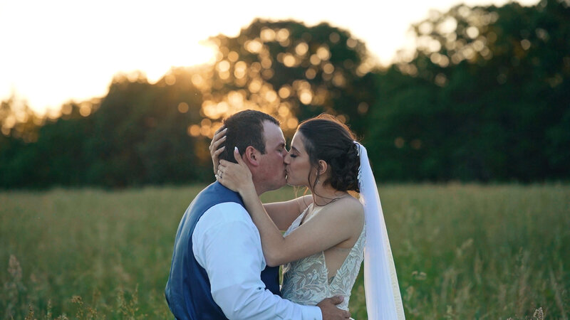 Bride and groom kissing at sunset in Missouri, captured during wedding portraits by Erhart Productions.