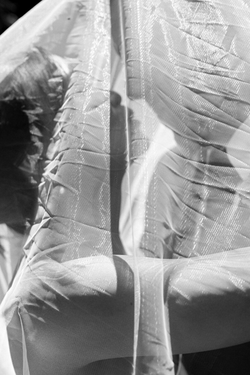 black and white photo of bride and groom about to kiss under her veil after they got married