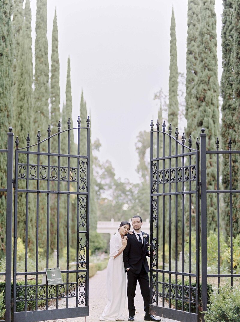 Bride and groom posing with gorgeous estate black gates