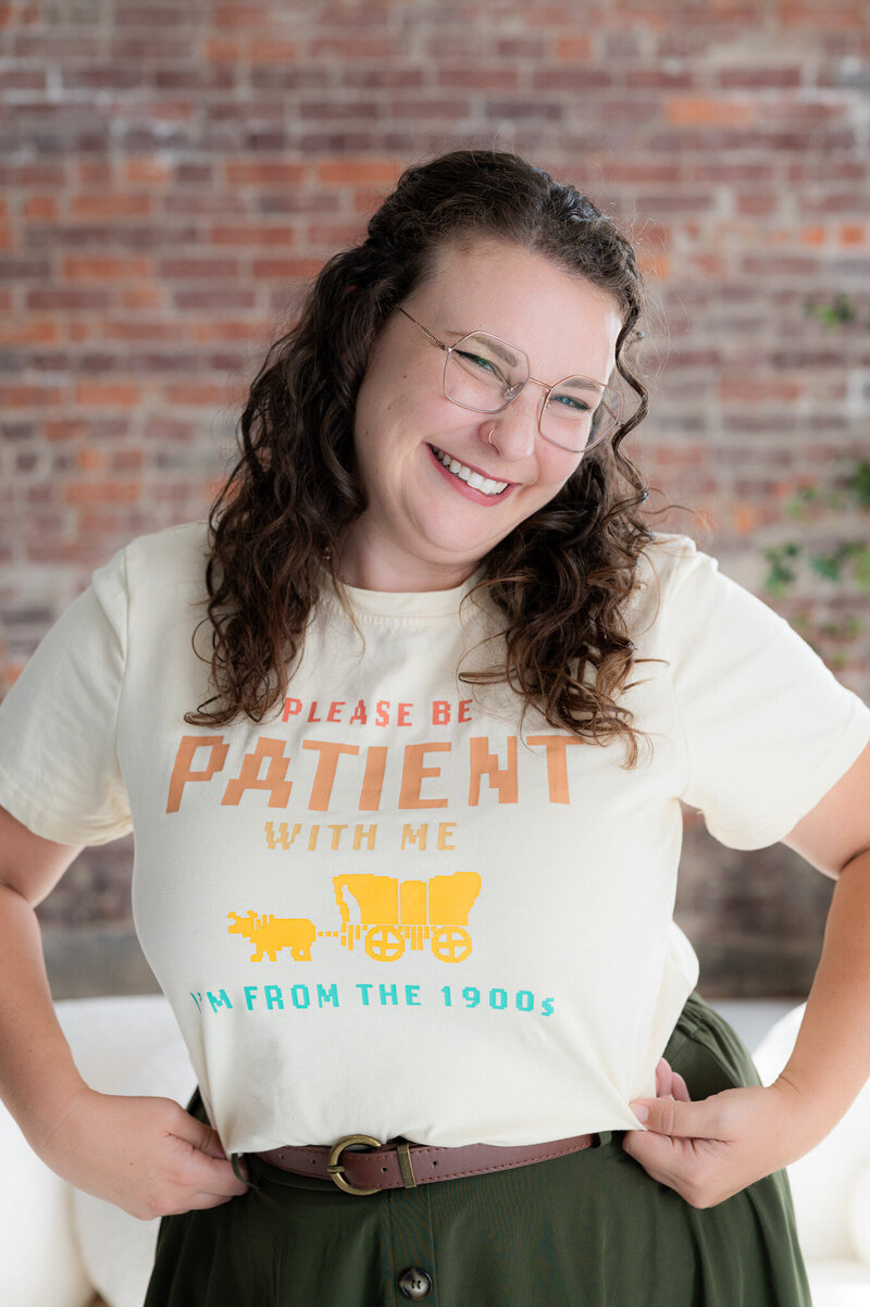 Emma Males Photo VA standing in front of a brick wall smiling sharing information on marketing photography business