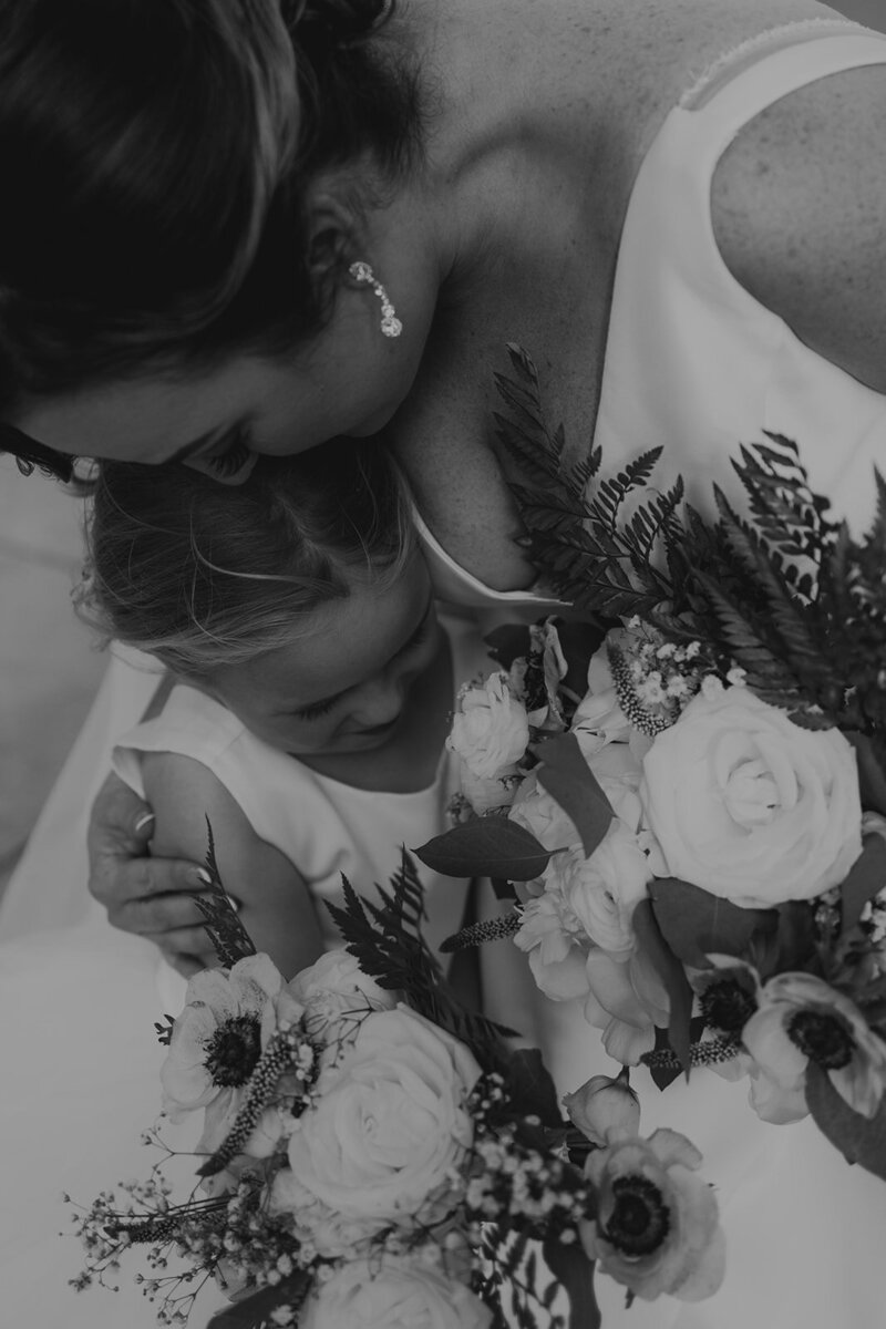 mother hugs her daughter with flowers in hand