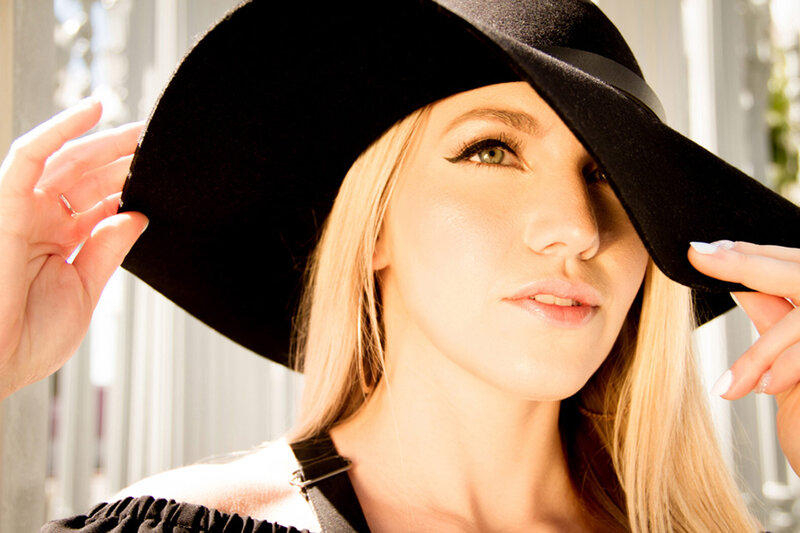 Musician Portrait Jenna NATION Los Angeles closeup holding edges of wide brim black hat while wearing it