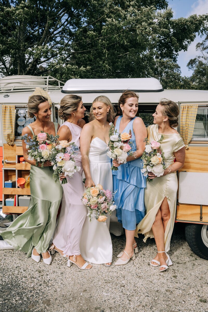bridesmaids in mismatched pastel dresses in front of orange kombi with pastel bouquets near gore new zealand