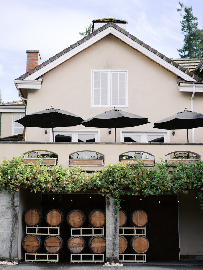 Exterior of the venue featuring barrel decor and terrace umbrellas