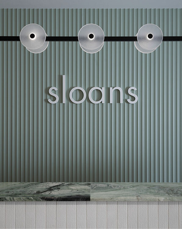 Minimalist reception area with Sloan's logo and marble detailing, reflecting professional hair consultations and keratin treatments.