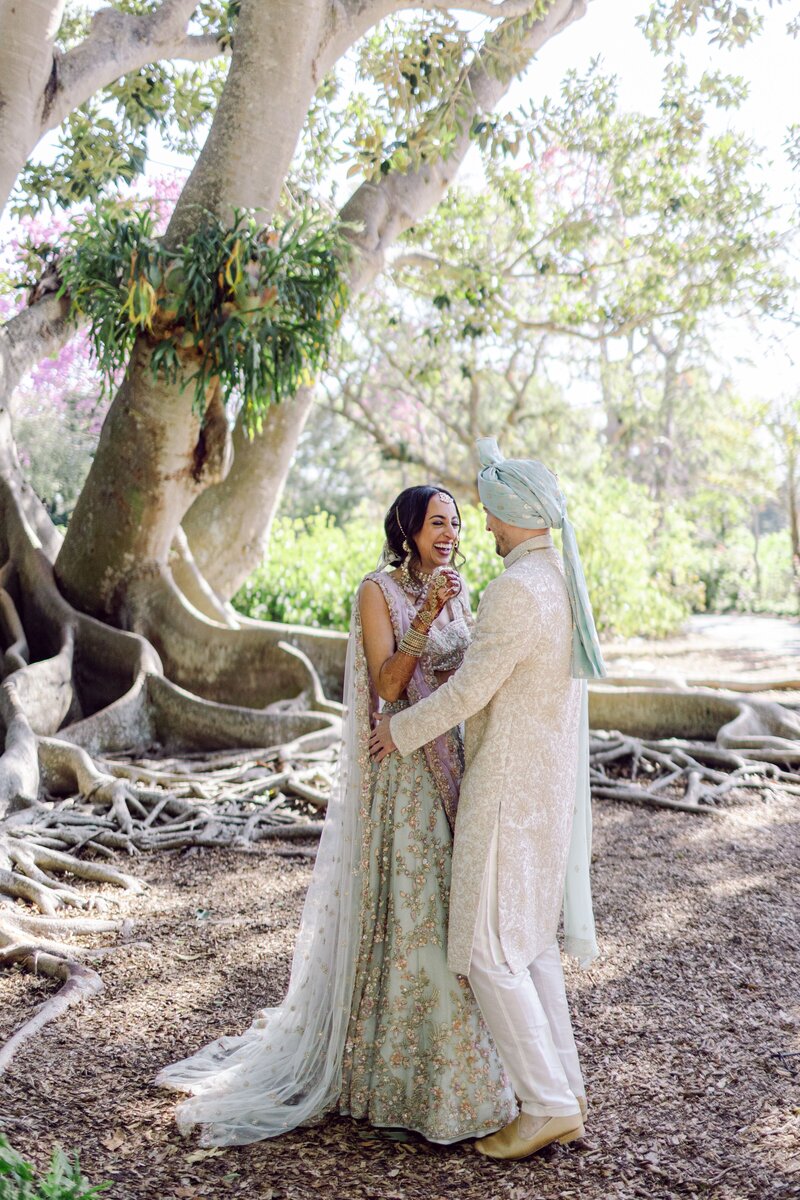 Indian married couple in traditional dress embracing in front of trees and grenery