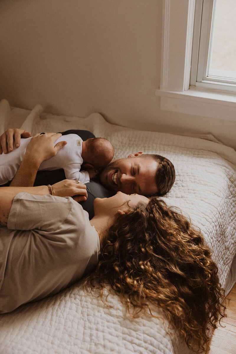 New parents look into each others eyes as their newborn baby lays on their stomachs