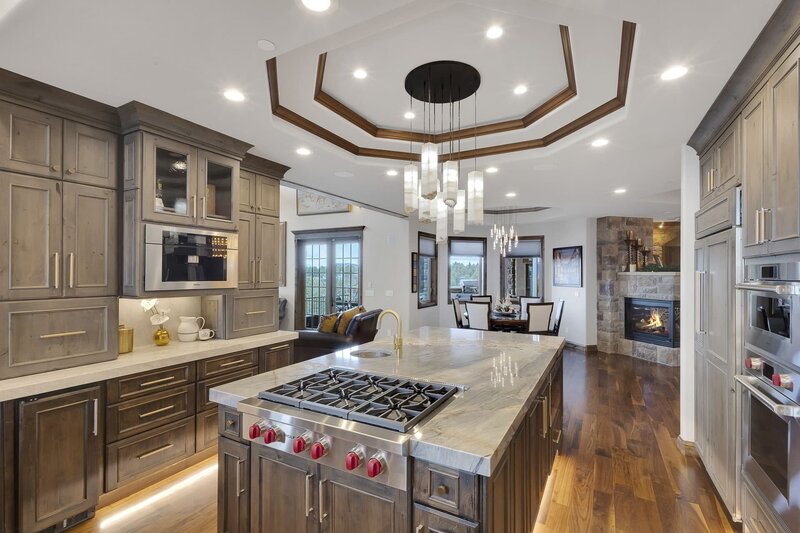 A large warm kitchen with a detailed ceiling and wooden cabinets .