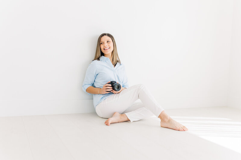 a photographer sits on the floor of a photo studio in Austin holding her camera.