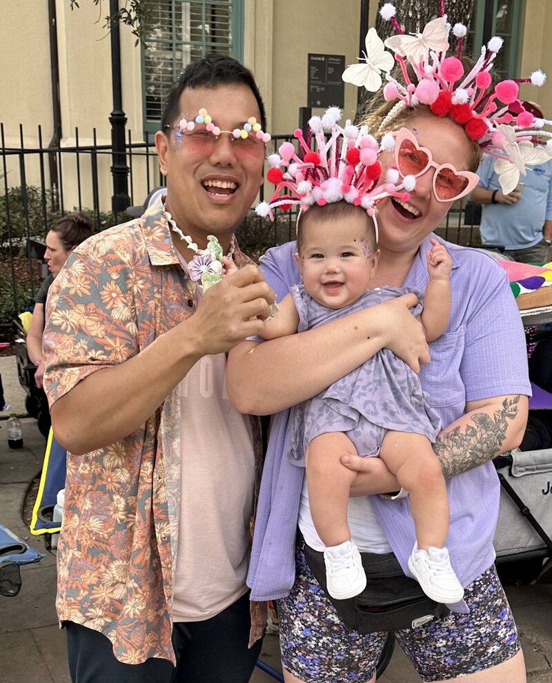 Olivia Yuen and her family dressed in festive outfits, enjoying a street parade with bright and playful headpieces.