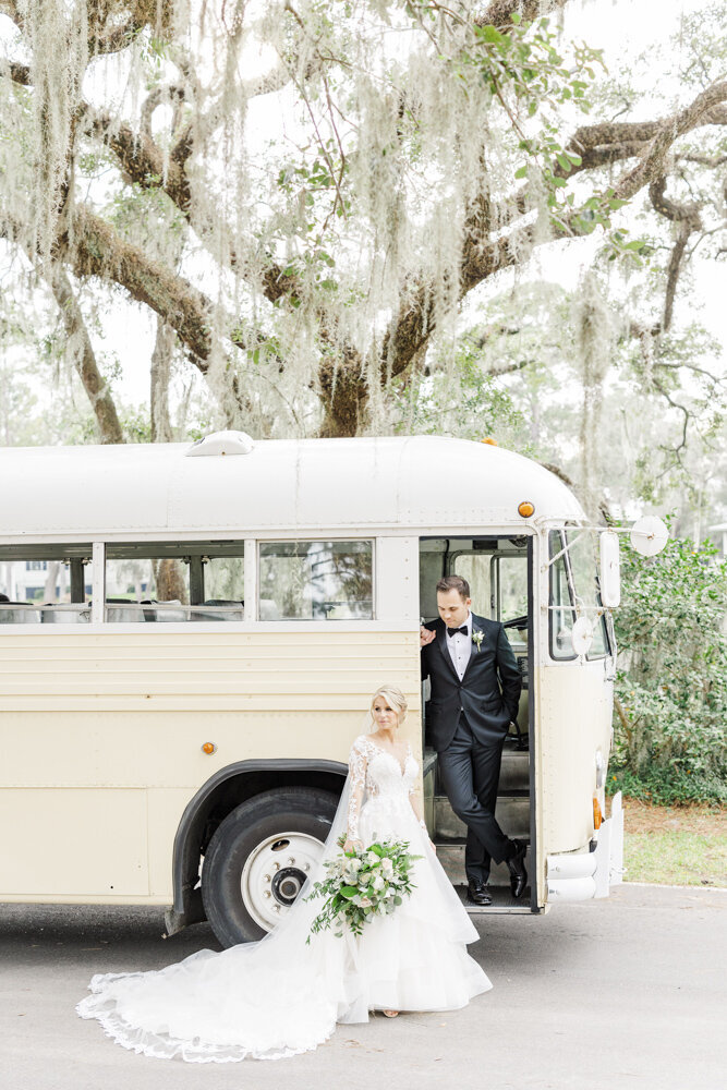 bride and groom posing by a vintage bus