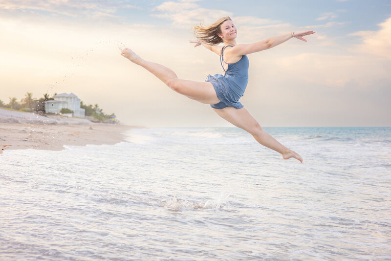 high school senior dancing leap on the beach in front of Disney resort 