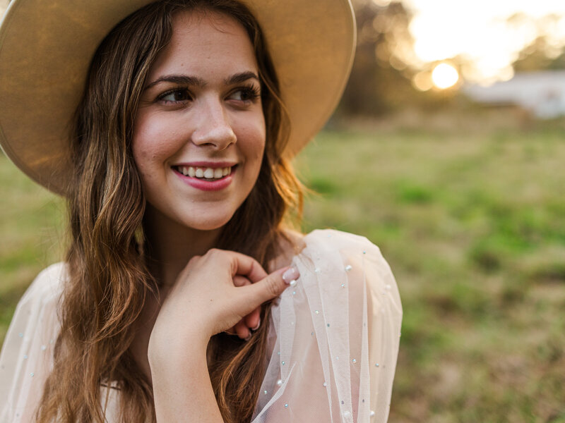 young girl facing camera with hand next to chin and looking off from the camera