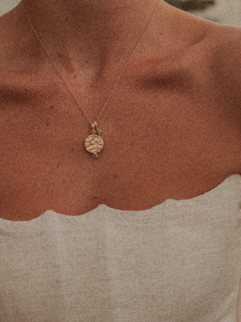 An up-close photo of a woman's neckline with a golden necklace