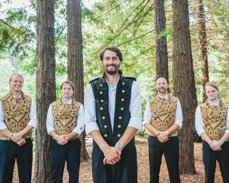 Groomsmen stand on both sides of Groom as he stands in the middle