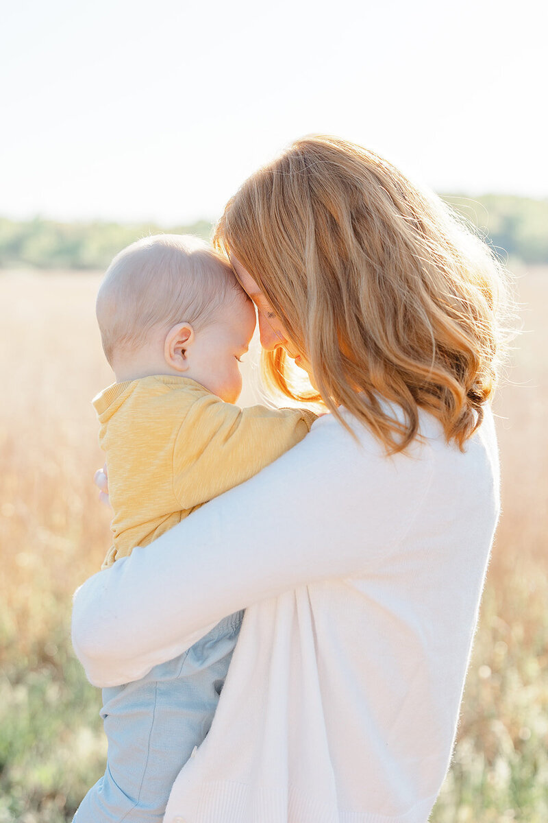 mom touching her forehead with her baby’s taken by a Gainesville, Virginia family photographer