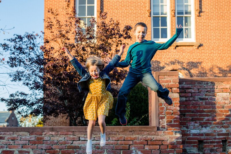 Two kids jump up in the air off of a bench