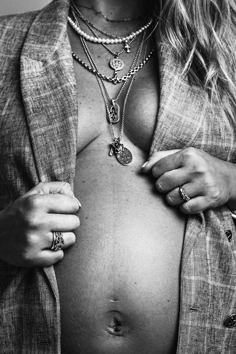 photo noir et blanc d'une femme enceinte avec des bijoux et un blazer