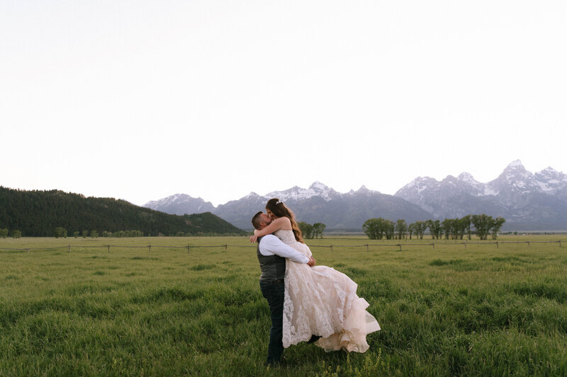 Bride and groom sharing a romantic moment in a mountain meadow during their intimate Grand Teton wedding, photographed by Seattle destination wedding photographer Rachael Marie Photography
