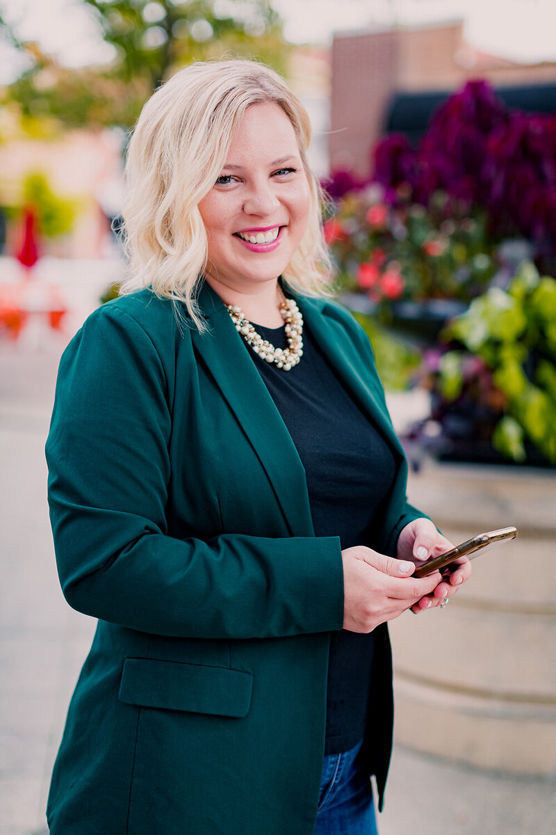 Woman smiling while holding her phone in a park