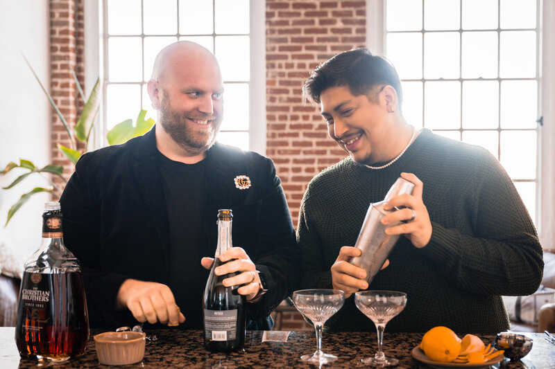 A gay couple stands together preparing to make themselves cocktails behind the bar of their kitchen in their apartment in Downtown Roanoke.