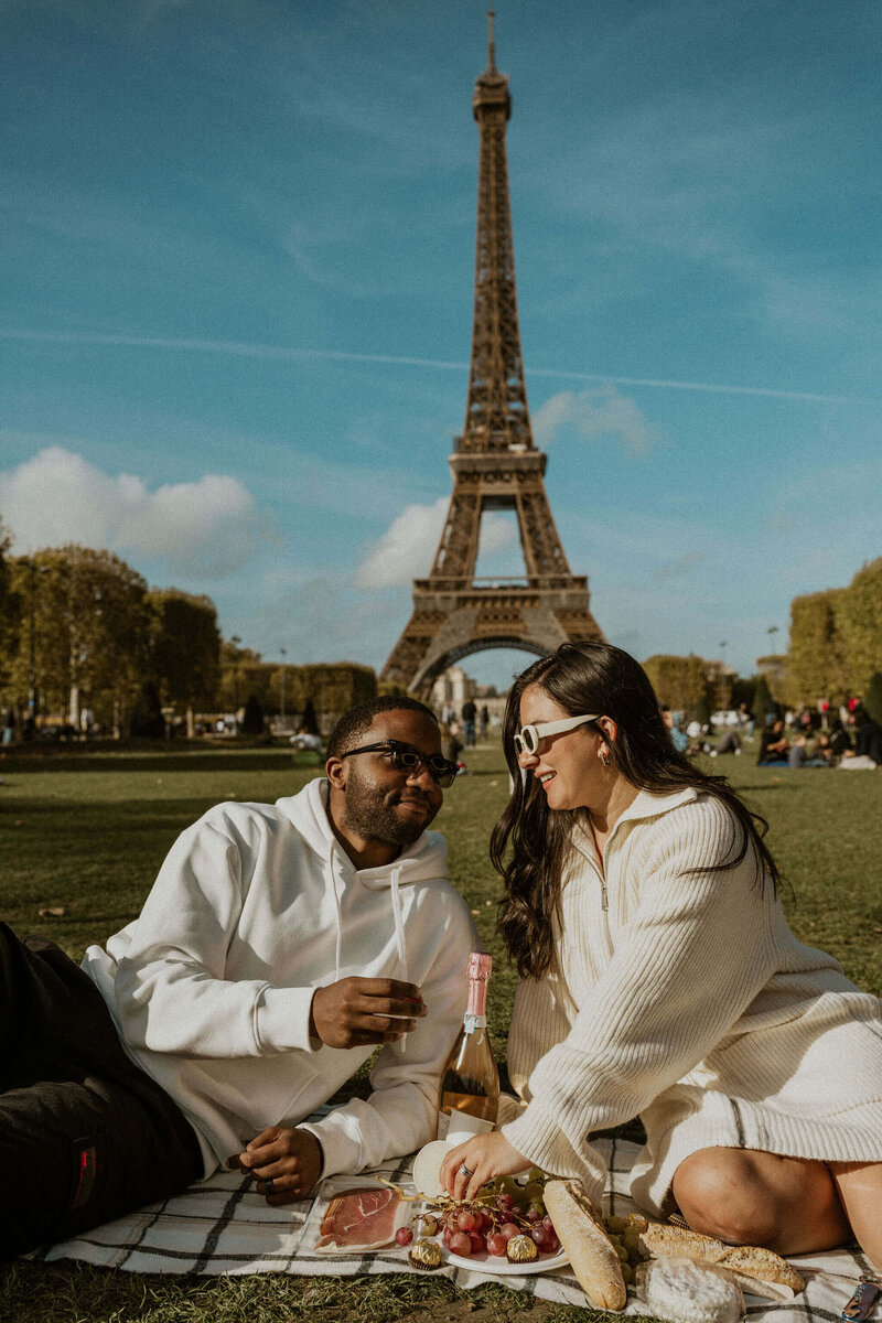 Newly engaged couple enjoying a picnic at the base of the Eiffel Tower in Paris France