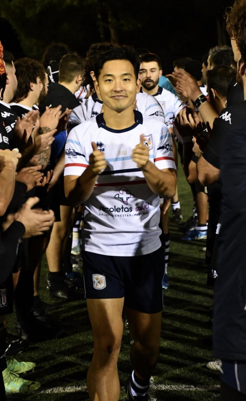 Yasushi Katsuta walking off the rugby field smiling, surrounded by teammates before a match