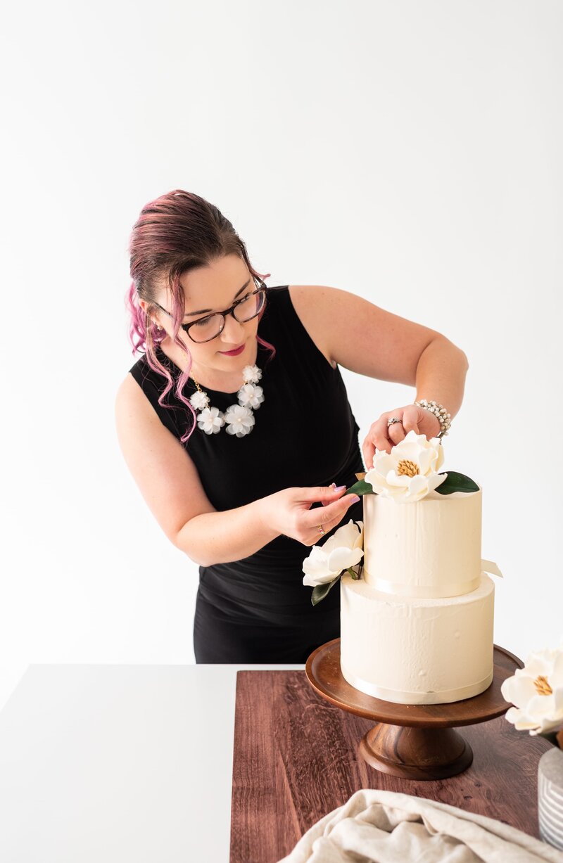 Cake decorator Styling a cascade of Sugar flowers On a wedding cake