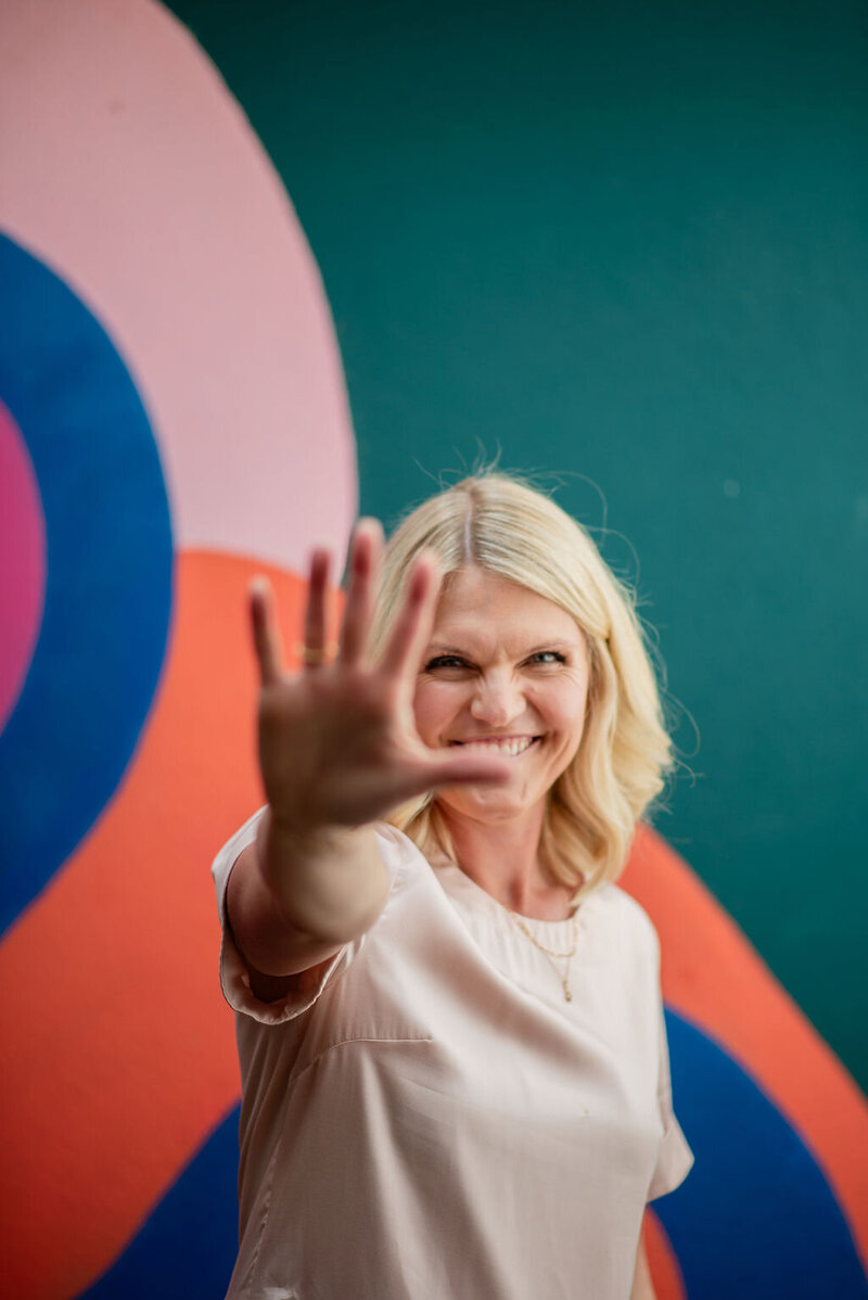 Woman holding phone streaming the High Vibe CEO Mama podcast by Emily Collins.