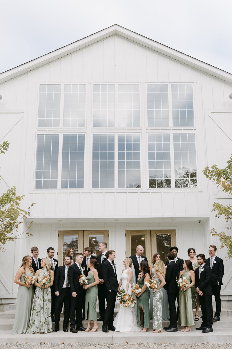 full bridal party smiles at each other