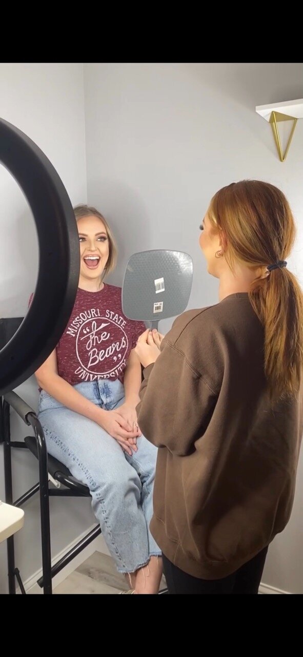 A makeup artist holding up a mirror for a client.