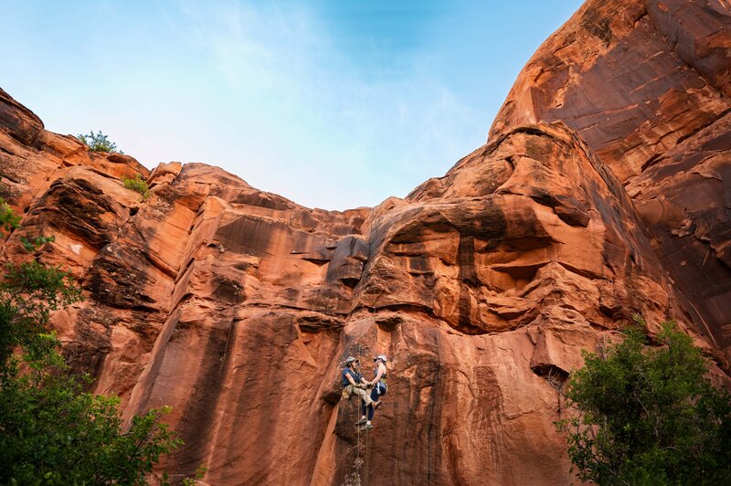 Couple goes rappelling in Moab during their adventure engagement session.
