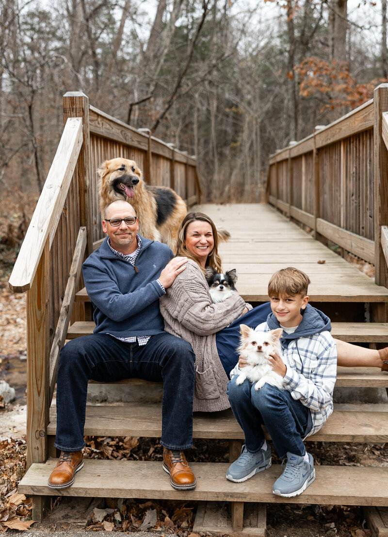 Family with their dogs sitting on a wooden bridge stairs. 
