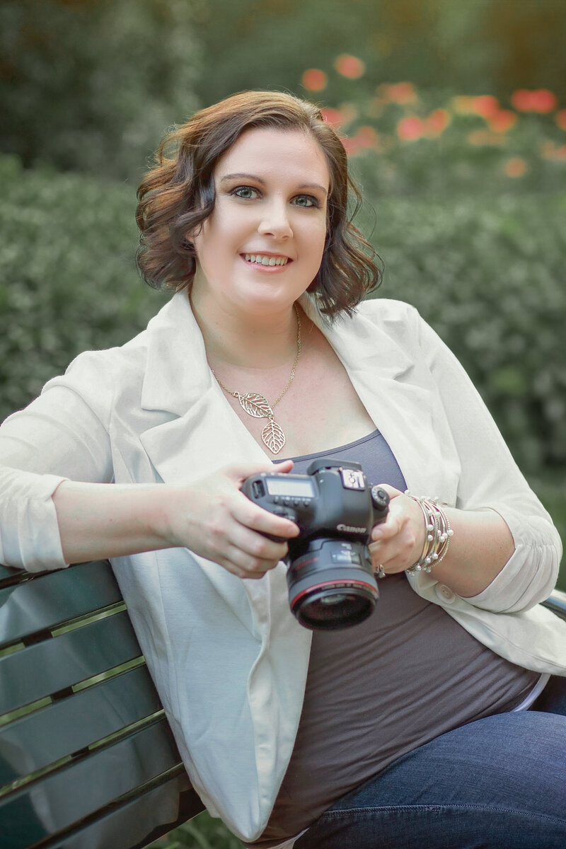 Ella Grace Richards, a Chicago-based wedding and event photographer, smiles while looking down at her camera, reflecting her passion for storytelling through elegant and authentic imagery.