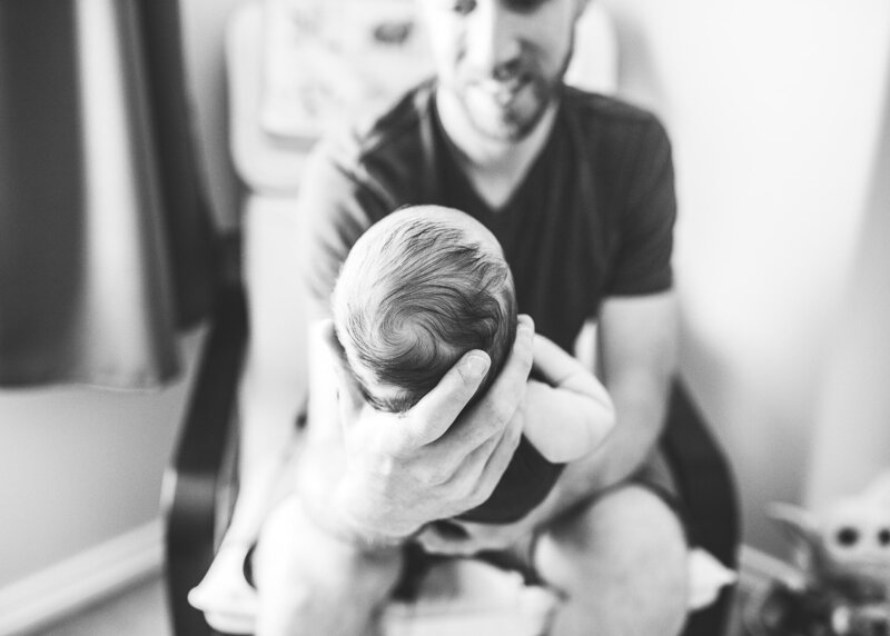 Black and white image of dad holding newborn baby in his hands by Portland newborn Photographer.