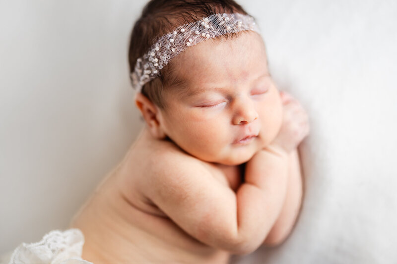 Sleeping newborn baby posed on white background at Allison Reilly's Union County, NJ photo studio.