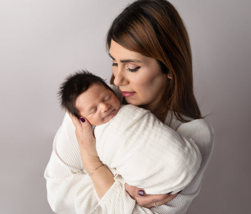 mom holding newborn baby boy for studio portraits