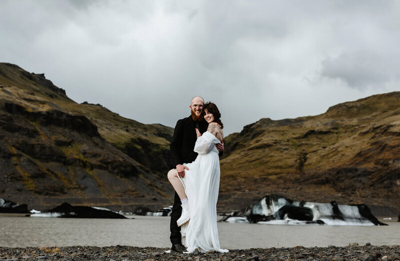 newlywed couple is posing in front of a glacier in Iceland