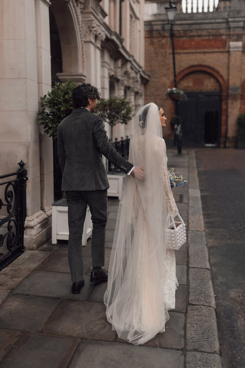 Married couple walks hand in hand outside their London wedding venue st etheldreda's church after their intimate ceremony.