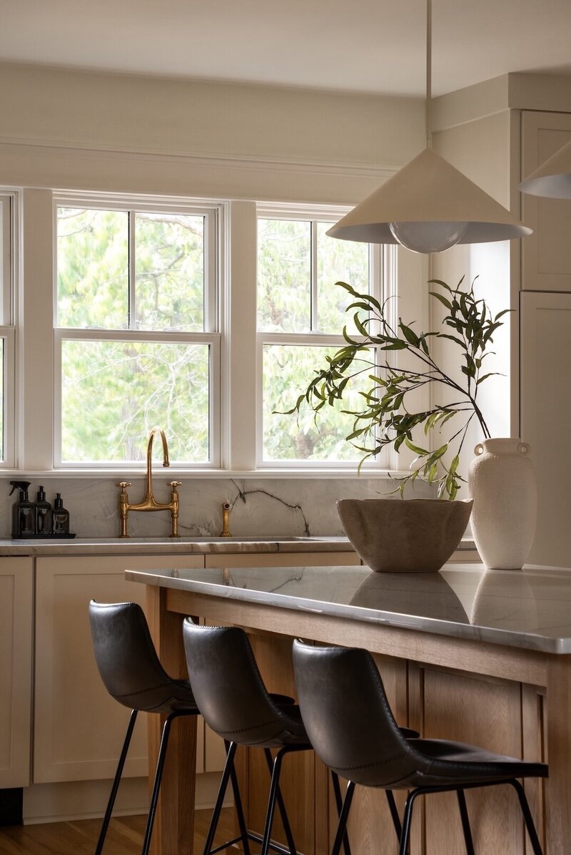 Kitchen island corner featuring farmhouse sink, cold faucet, and bright backyard window with natural light flooding the space.