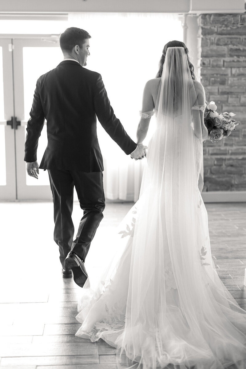 A bride and groom walking away, holding hands